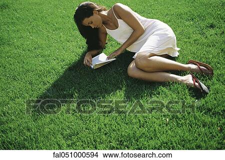 Young woman lying on grass reading book View Large Photo Image Picture - Young woman lying on grass reading book. Fotosearch
