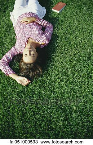 Young woman napping on grass, book lying on ground beside her View Large Photo Image Stock Image - Young woman napping on grass, book lying on ground beside her. Fotosearch