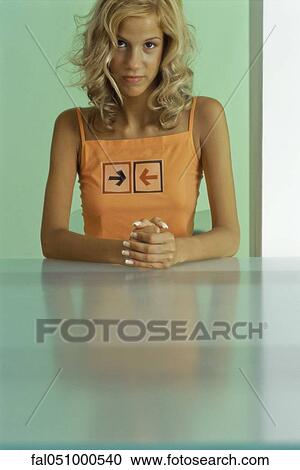 Young woman sitting with hands clasped together, looking at camera View Large Photo Image Stock Image - Young woman sitting with hands clasped together, looking at camera. Fotosearch