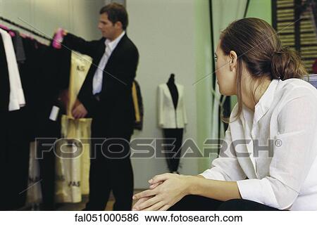 Young woman watching man looking at clothes in store View Large Photo Image Stock Photograph - Young woman watching man looking at clothes in store. Fotosearch