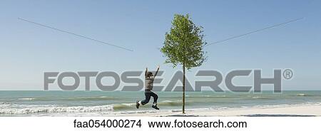 Boy jumping in midair on beach View Large Photo Image Picture - Boy jumping in midair on beach. Fotosearch