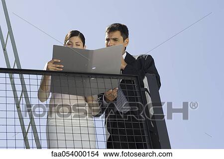 Business associates reading document together on balcony View Large Photo Image Picture - Business associates reading document together on balcony. Fotosearch
