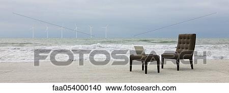 Chair and laptop computer on beach, wind turbines visible in distance View Large Photo Image Stock Image - Chair and laptop computer on beach, wind turbines visible in distance. Fotosearch