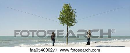 Stock Photo - Children communicating with tin can phones at the beach. Fotosearch