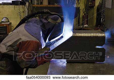 Stock Image - Coated textile plant, maintenance workshop, welder performing arc welding. Fotosearch