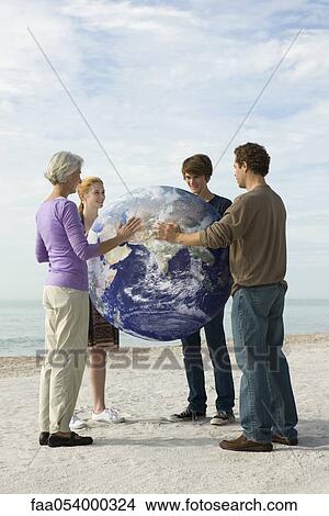 Picture - Ecology concept, four people placing hands on earth together. Fotosearch