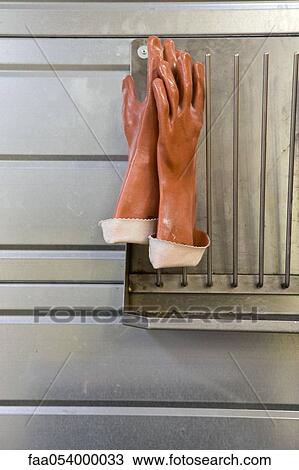 Stock Image - Fabric coating plant, rubber gloves drying on rack. Fotosearch
