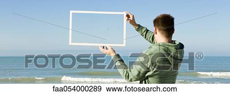 Gulls flying above sea framed in picture frame held aloft by man on beach View Large Photo Image Stock Photo - Gulls flying above sea framed in picture frame held aloft by man on beach. Fotosearch