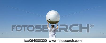 Stock Image - Holding aloft globe displaying image of single tree. Fotosearch