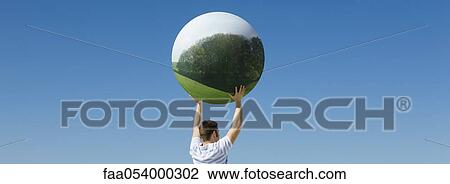 Holding aloft globe displaying image of forest View Large Photo Image Stock Image - Holding aloft globe displaying image of forest. Fotosearch