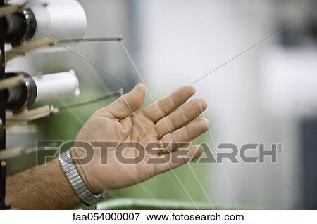 Stock Photo - Machinist checking thread tension on loom in weaving mill. Fotosearch