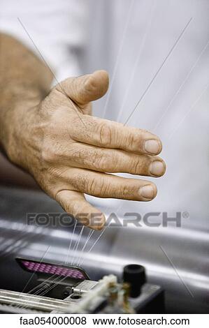 Stock Photo - Machinist checking thread tension on loom in weaving mill. Fotosearch