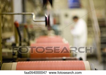 Stock Photo - Recyclable composite textile fabrication department of factory, machinist working on thread coating machine. Fotosearch
