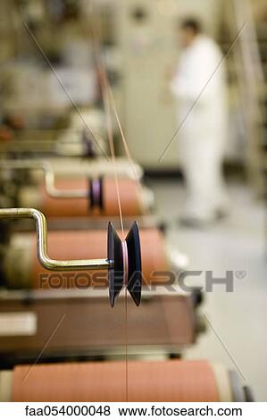 Stock Photo - Recyclable composite textile fabrication department of factory, machinist working on thread coating machine. Fotosearch