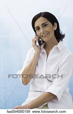Stock Photo - Woman using cell phone, smiling at camera. Fotosearch