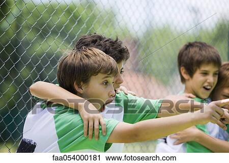 Stock Image - Young teammates embracing and pointing in disbelief. Fotosearch