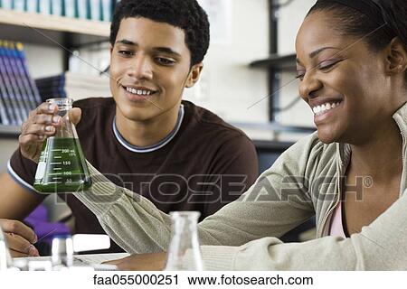 Stock Image - Classmates conducting experiment together in chemistry class. Fotosearch