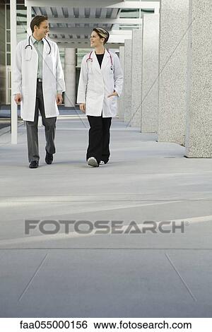 Stock Photograph - Doctors chatting and walking together along hospital corridor. Fotosearch