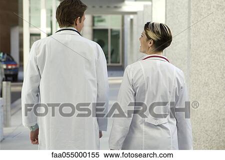 Doctors chatting and walking together along hospital corridor, rear view View Large Photo Image Stock Photography - Doctors chatting and walking together along hospital corridor, rear view. Fotosearch