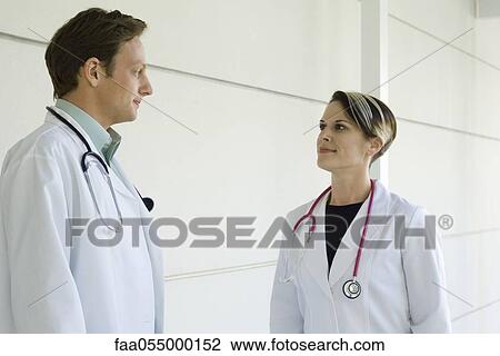 Doctors chatting together in hospital corridor View Large Photo Image Stock Image - Doctors chatting together in hospital corridor. Fotosearch