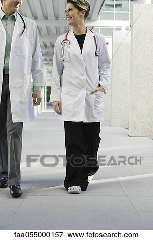 Female doctor walking with colleague along hospital corridor View Large Photo Image Stock Photo - Female doctor walking with colleague along hospital corridor. Fotosearch