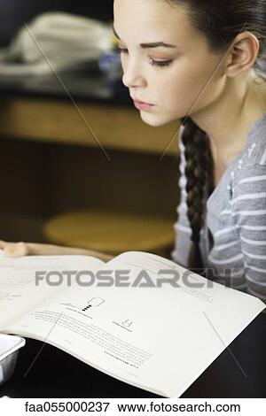 Stock Photo - Female student reading textbook. Fotosearch