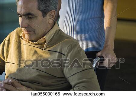 Man being pushed in wheelchair looking down contemplatively View Large Photo Image Stock Photography - Man being pushed in wheelchair looking down contemplatively. Fotosearch