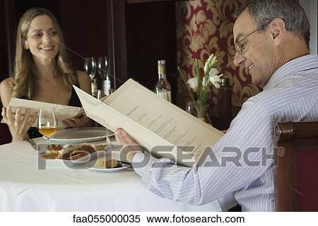 Mature couple in restaurant looking at menus View Large Photo Image Stock Photography - Mature couple in restaurant looking at menus. Fotosearch