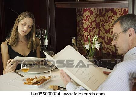 Mature couple looking at menus in restaurant View Large Photo Image Picture - Mature couple looking at menus in restaurant. Fotosearch