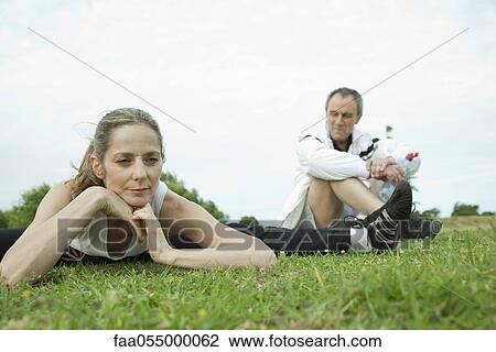 Stock Image - Mature couple stretching in park. Fotosearch