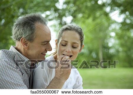 Mature couple together in park, man feeding woman View Large Photo Image Stock Photo - Mature couple together in park, man feeding woman. Fotosearch