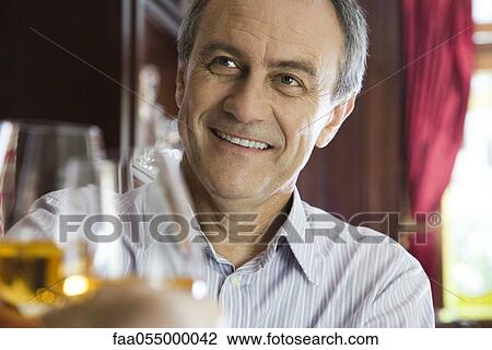 Mature man clinking glasses with companion in restaurant View Large Photo Image Stock Image - Mature man clinking glasses with companion in restaurant. Fotosearch