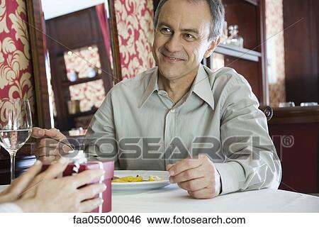 Mature man giving gift to woman in restaurant View Large Photo Image Stock Photograph - Mature man giving gift to woman in restaurant. Fotosearch