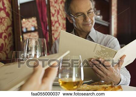 Stock Photo - Mature man looking at menu in restaurant. Fotosearch