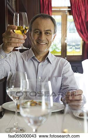 Mature man raising glass of wine in celebration View Large Photo Image Stock Image - Mature man raising glass of wine in celebration. Fotosearch