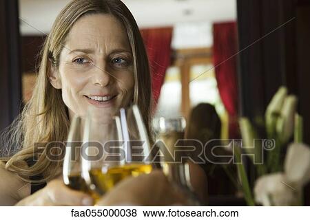 Mature woman clinking wine glasses with companion in restaurant View Large Photo Image Stock Photo - Mature woman clinking wine glasses with companion in restaurant. Fotosearch