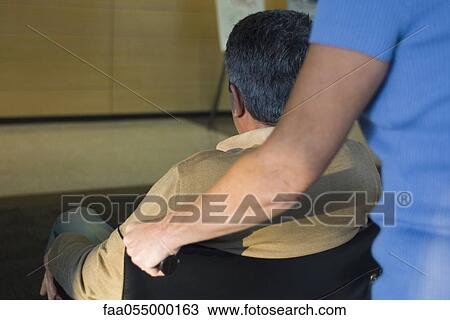 Stock Image - Pushing man in wheelchair. Fotosearch