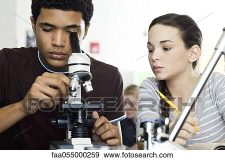 Stock Photo - Student looking through microscope in science class. Fotosearch