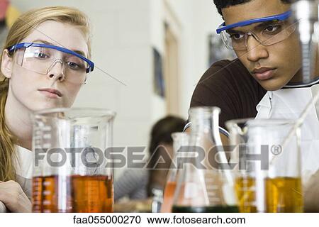 Stock Image - Students conducting experiment in chemistry class. Fotosearch