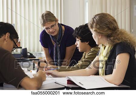 Stock Image - Teacher assisting high school students. Fotosearch
