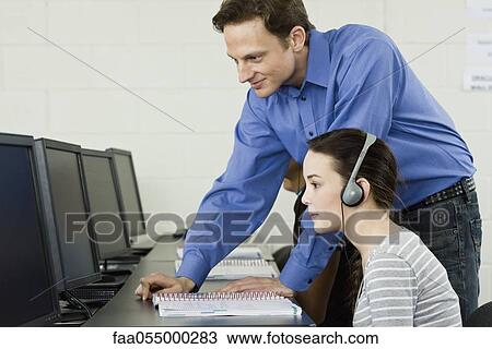 Teacher assisting student in computer lab View Large Photo Image Stock Image - Teacher assisting student in computer lab. Fotosearch