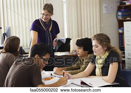 Teacher helping high school students with classwork View Large Photo Image Stock Image - Teacher helping high school students with classwork. Fotosearch