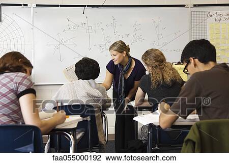 Stock Image - Teacher helping student in math class. Fotosearch