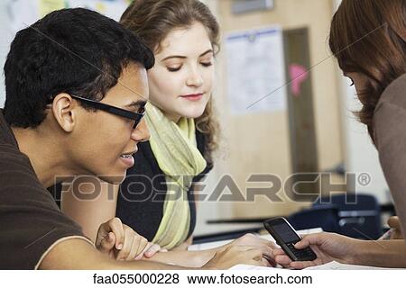 Teen boy showing cell phone to female friends View Large Photo Image Stock Photo - Teen boy showing cell phone to female friends. Fotosearch