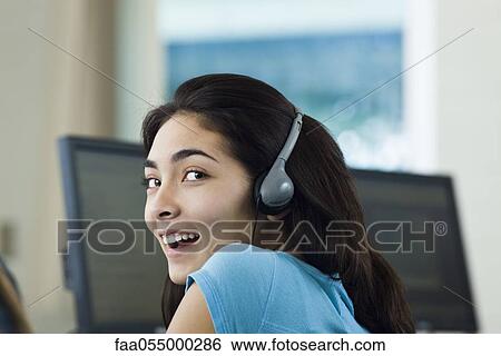 Teen girl listening to headphones, smiling over shoulder at camera View Large Photo Image Stock Photograph - Teen girl listening to headphones, smiling over shoulder at camera. Fotosearch
