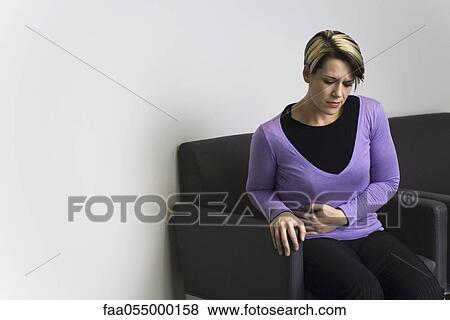 Woman sitting in hospital waiting room holding stomach View Large Photo Image Stock Photo - Woman sitting in hospital waiting room holding stomach. Fotosearch