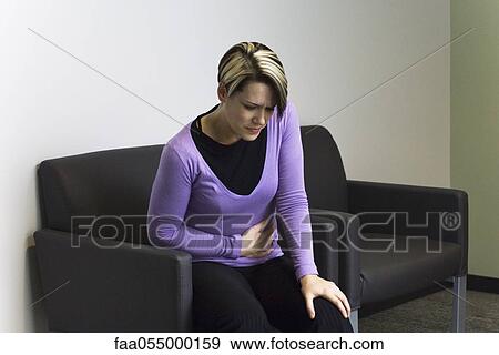 Woman sitting in hospital waiting room holding stomach View Large Photo Image Stock Photo - Woman sitting in hospital waiting room holding stomach. Fotosearch