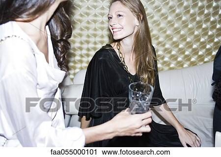 Young woman at night club chatting with friends View Large Photo Image Stock Image - Young woman at night club chatting with friends. Fotosearch