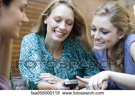 Stock Photo - Young woman showing cell phone to friends. Fotosearch