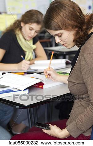 Young woman text messaging while in class View Large Photo Image Stock Image - Young woman text messaging while in class. Fotosearch